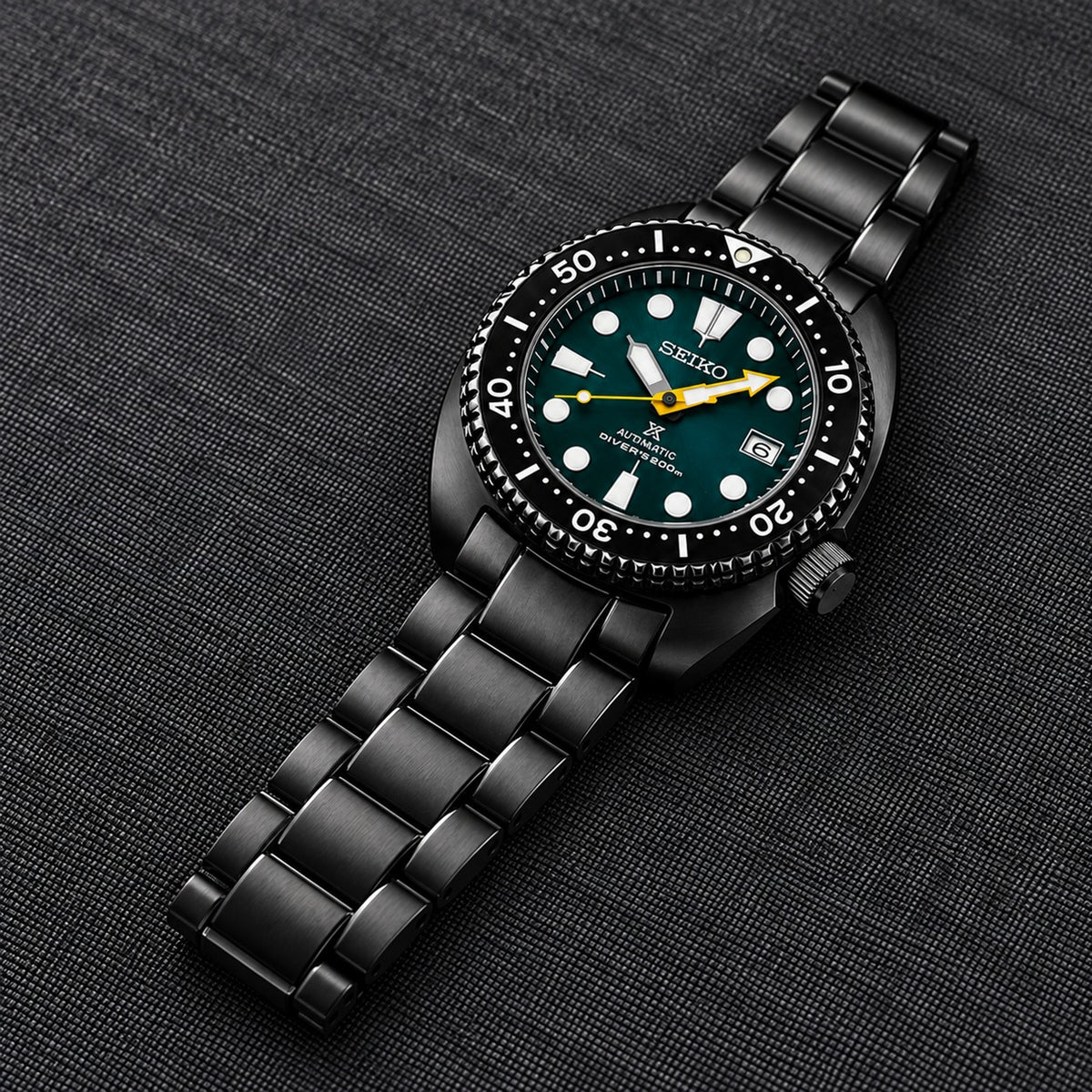 Black stainless steel bracelet on a black dive watch, close-up